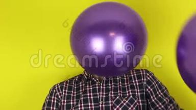 一个有趣，可爱的家伙正在积极地玩紫色气球。 一个漂亮的家伙在玩气球庆祝他的生日。 一个门廊